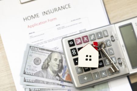 Home insurance application form, calculator, and money on the desk. 