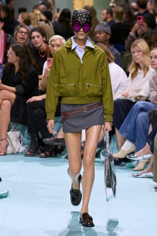 Model walking on the Prada runway wearing a sporty jacket.