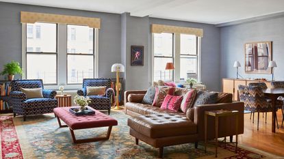 Powder blue open plan living room and diner with colorful accents on rugs and arm chairs