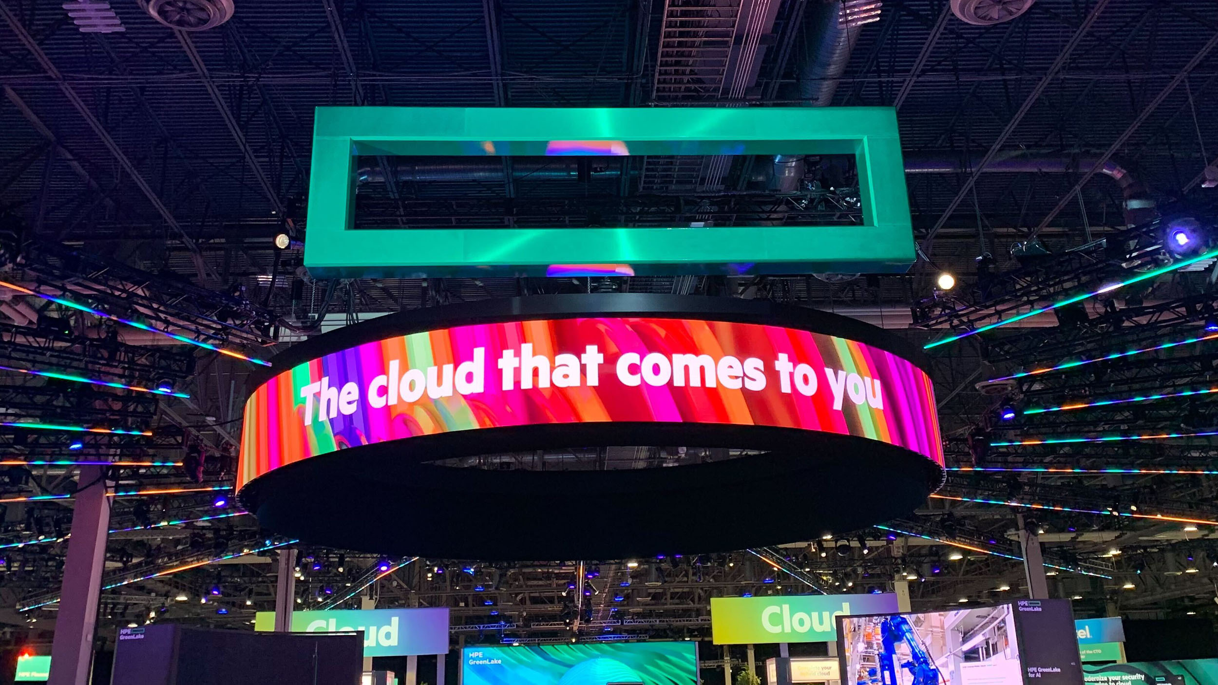 A large HPE logo hanging from the ceiling with a sign reading 