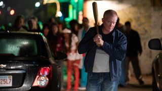 Anthony Michael Hall holds a bat in front of a crowd of onlookers in Halloween Kills.