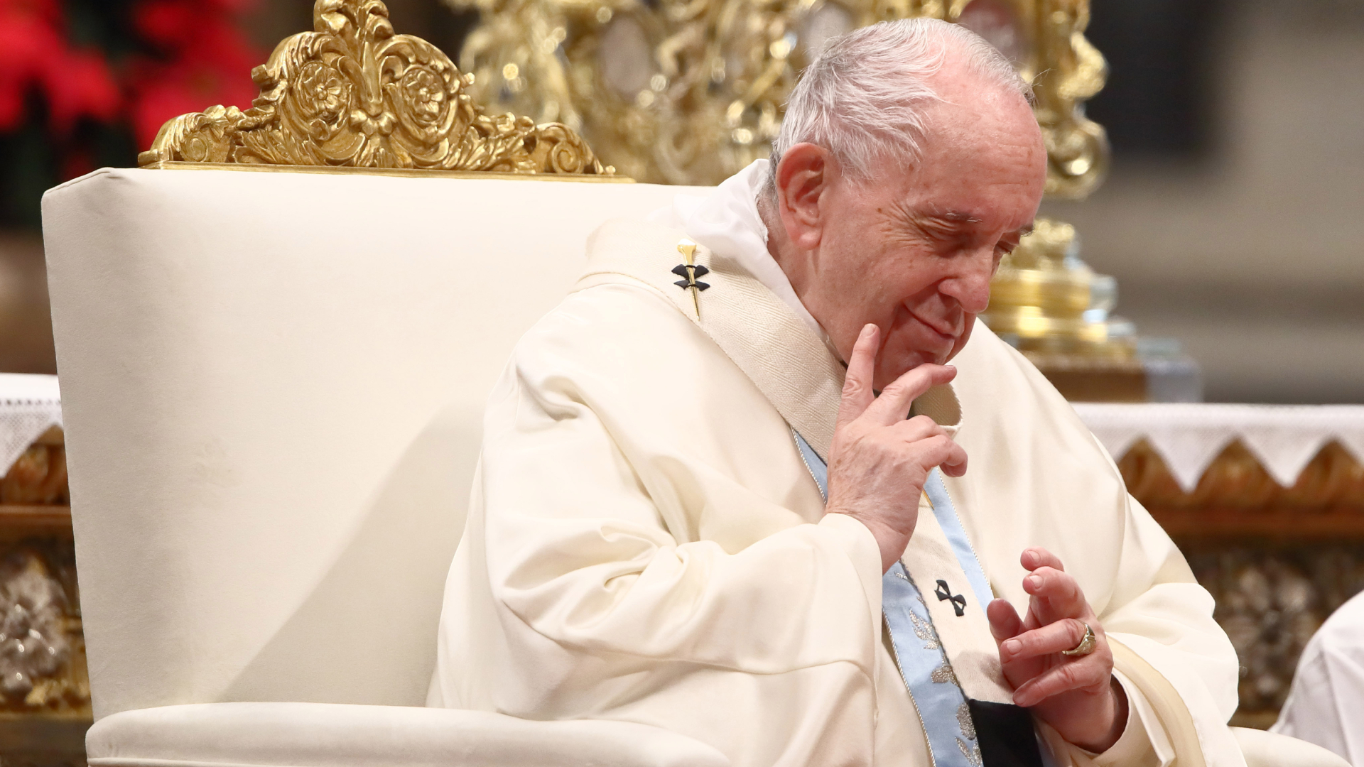 Le pape François assis sur une chaise avec les mains en l'air