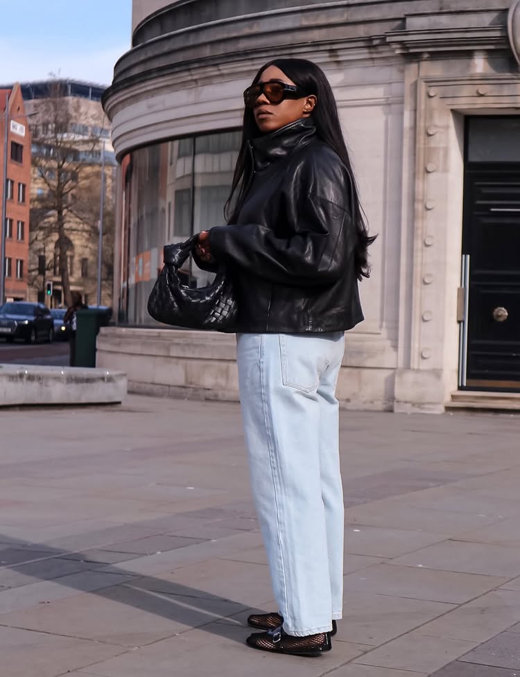 @_loissterling wears a pair of pale blue jeans with a leather funnel-neck jacket