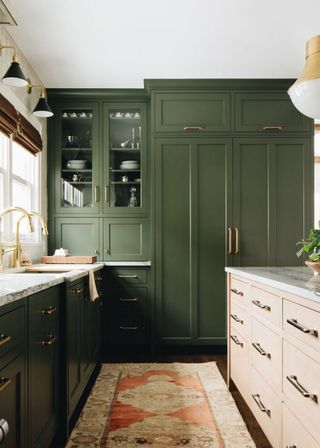 Green and cream kitchen ideas with a vintage Persian rug and gold faucets.