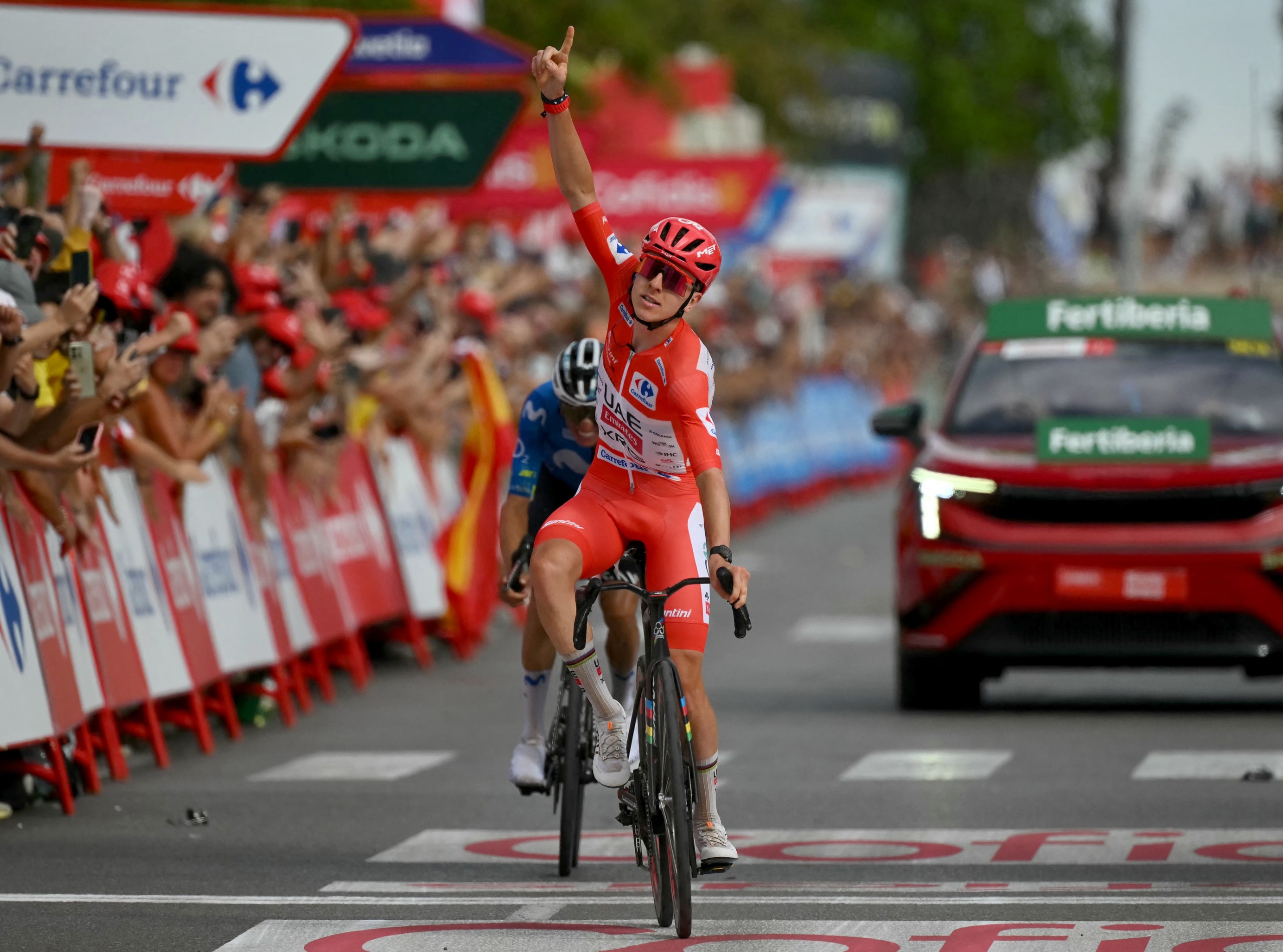 Tadej Pogacar celebrates with one arm raised as he wins stage 6 of the Vuelta with Mas just behind
