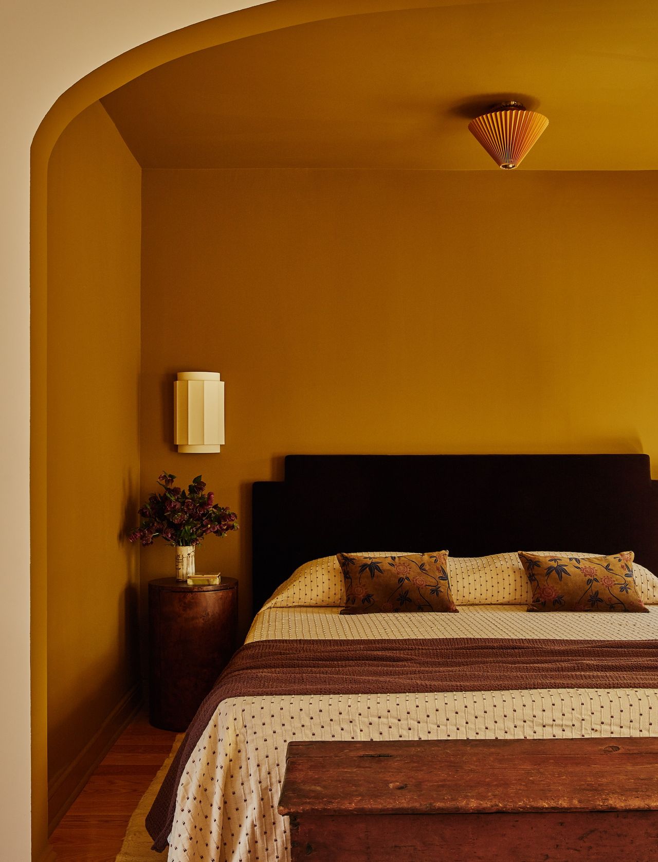 ochre bedroom with brown and cream bed linen, and warm woo accents