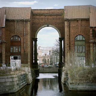 Two brick buildings connecting with arch over river