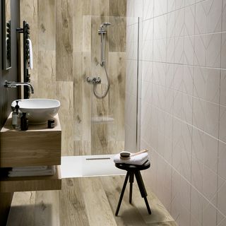 bathroom with wood walls with cream ceramic tile wash basin and shower