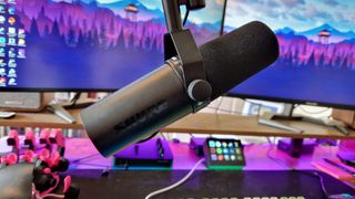 Shure SM7dB attached to a boom arm in front of two gaming monitors
