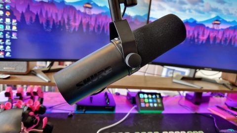 Shure SM7dB attached to a boom arm in front of two gaming monitors