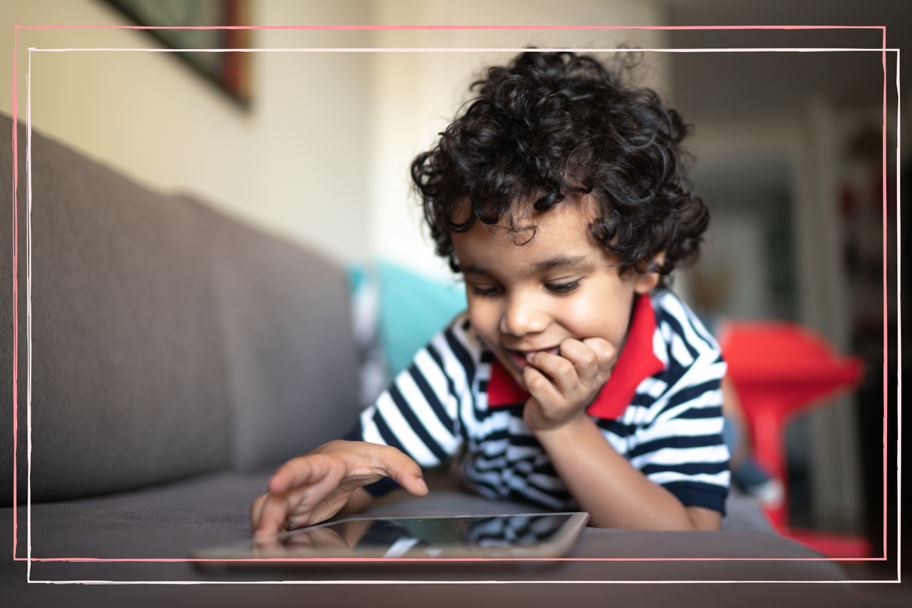 Young boy using a tablet at home while biting his nails