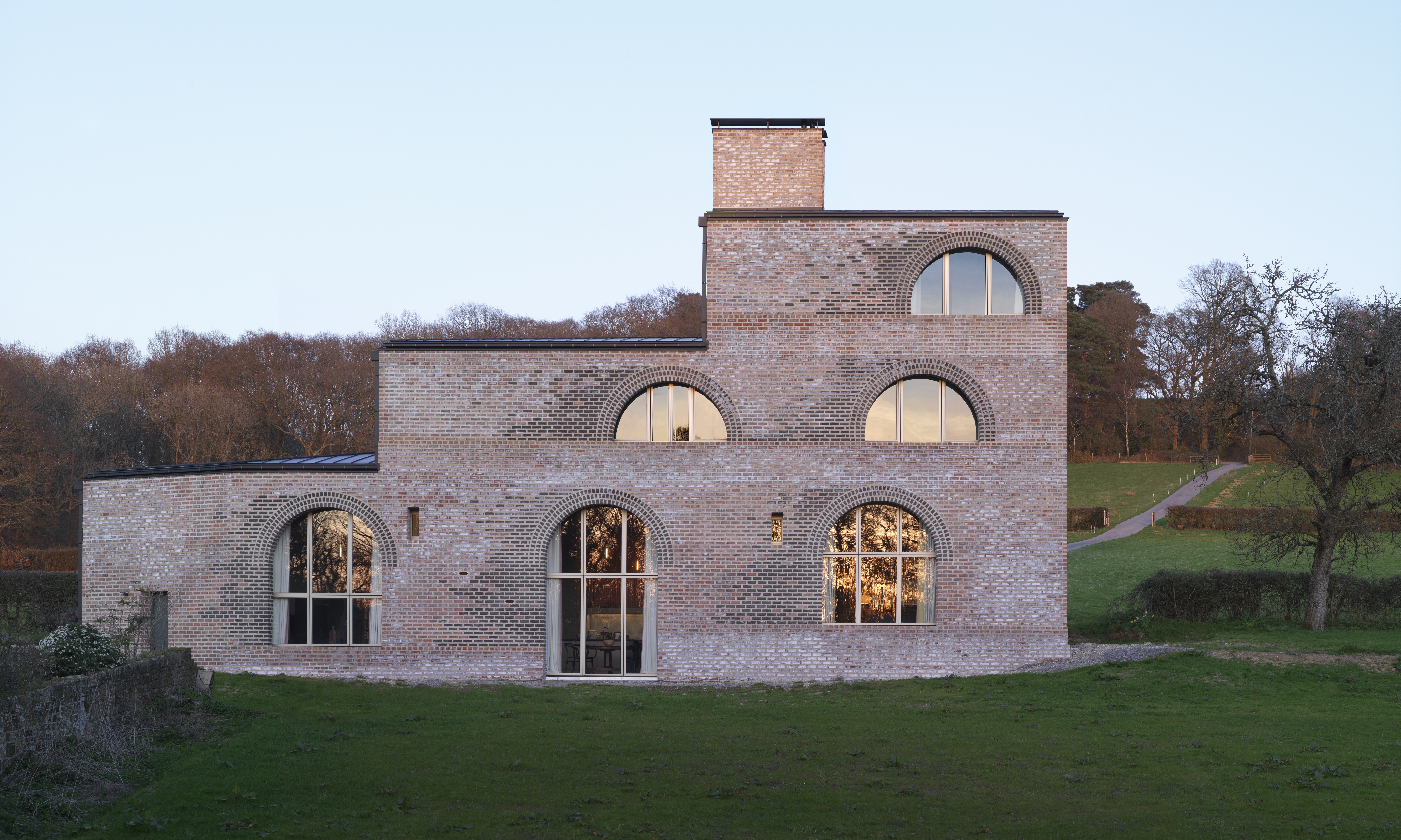 A large three storey farm house with a stepped design in a field.