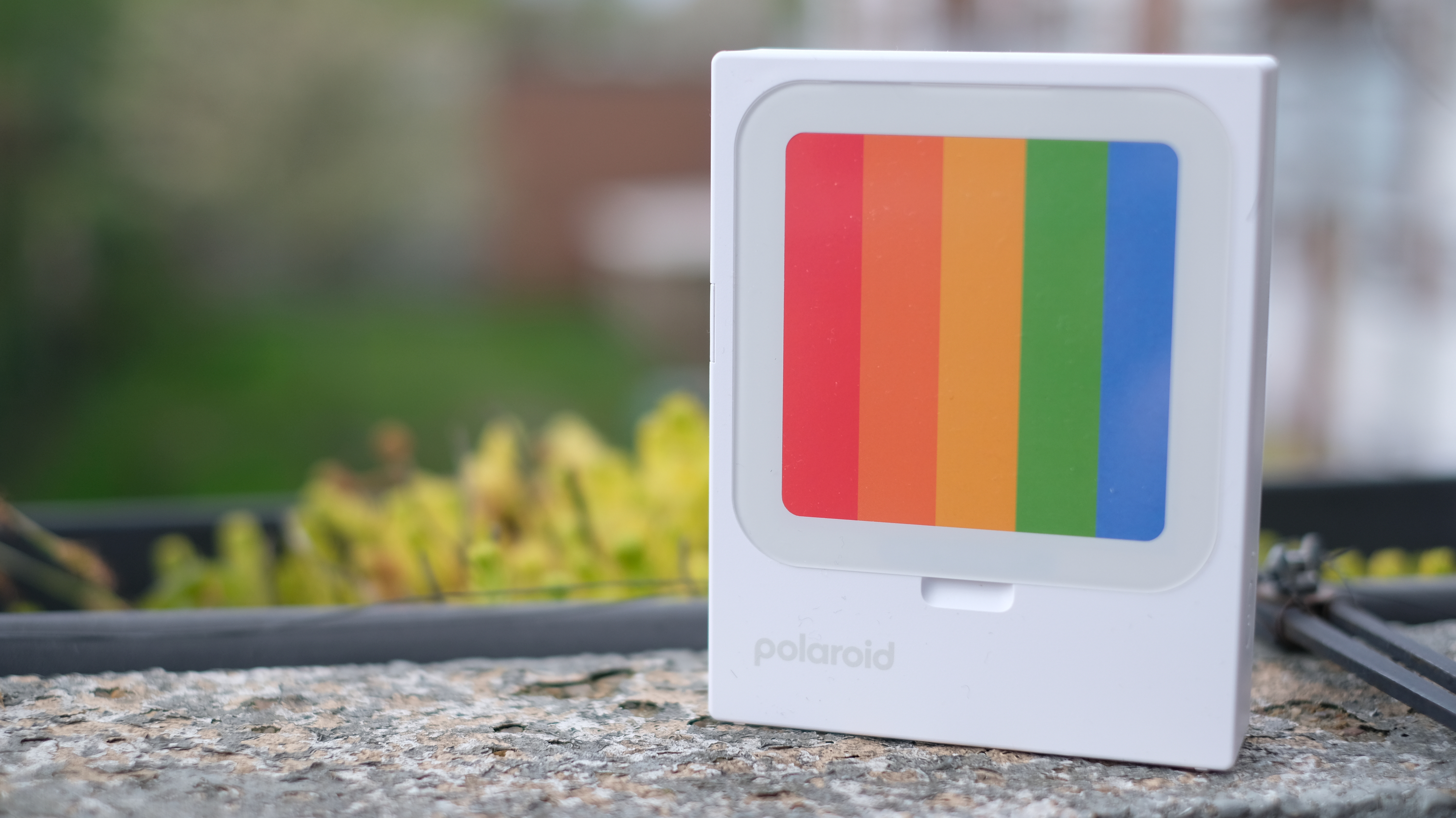 Photograph of Polaroid Hi-Print 3x3 mini instant printer standing with placeholder rainbow card in display slot.