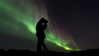 A couple silhouetted in front of the northern lights