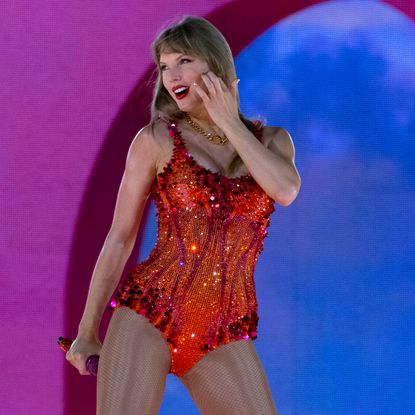 Taylor Swift onstage at the Eras Tour wearing a bodysuit with orange sequins by Versace