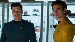 two men in starfleet uniforms stand in a laboratory