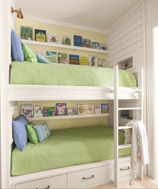 white bunk beds with wood panelled walls behind and book shelves, green bedding