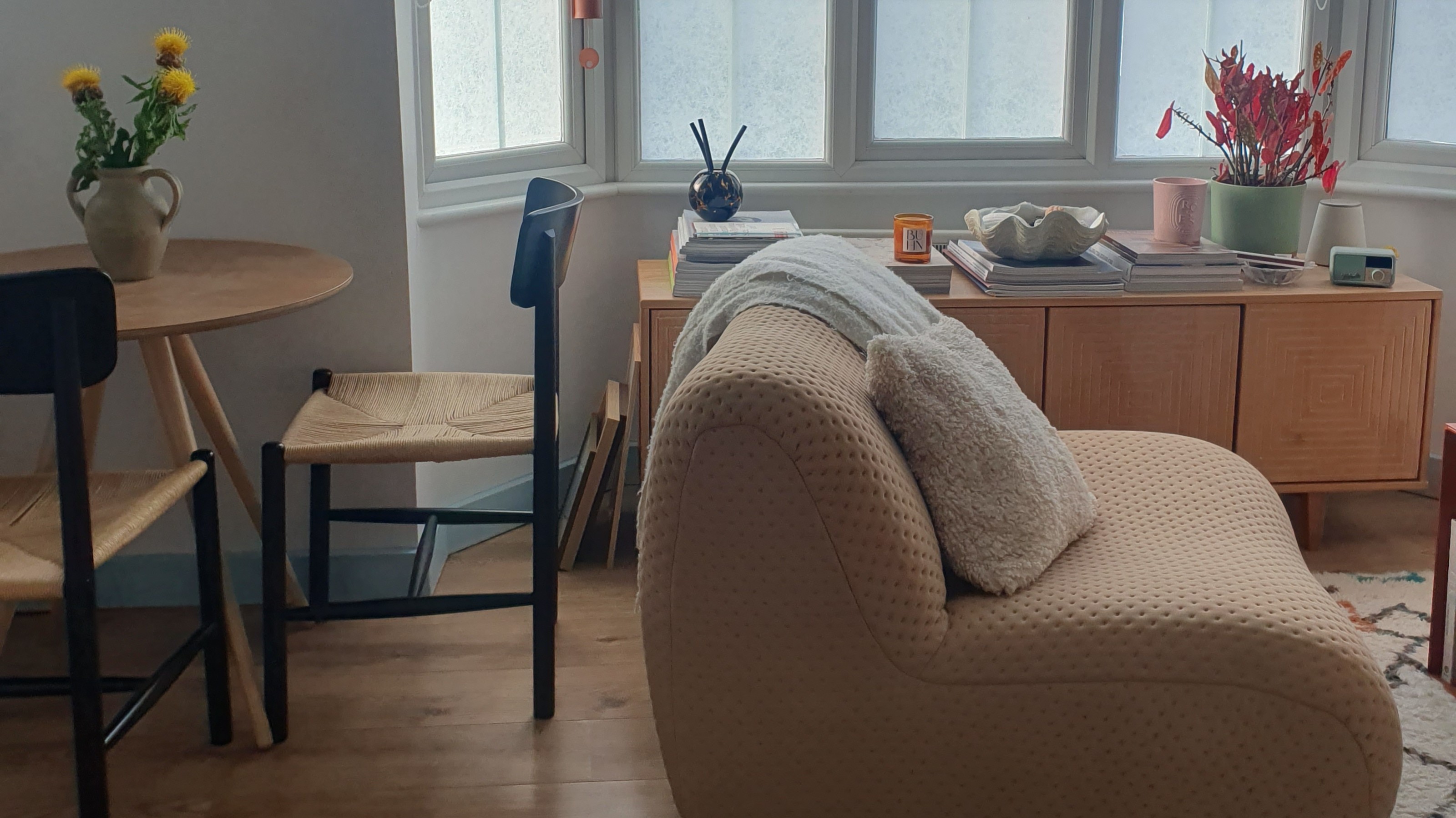My dining area with a round dining table and black woven chairs and my living area with the King Living 1977 sofa module used as an armchair