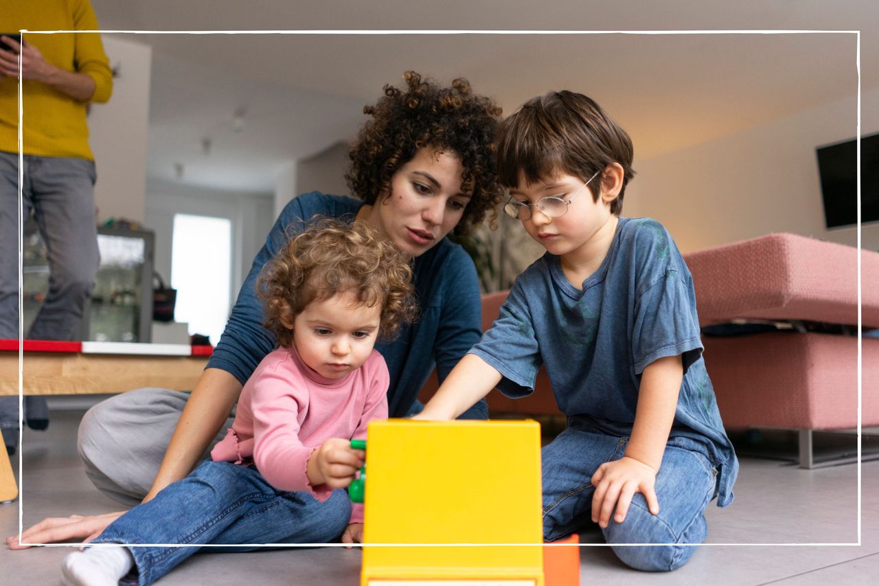 mother playing with children on the floor at home. They are playing with a toy till