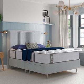 The Sealy Newton Posturepedic mattress in a bedroom with a grey upholstered bed frame