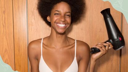 A woman holding a hair dryer and smiling to illustrate how to make your blowout last longer 