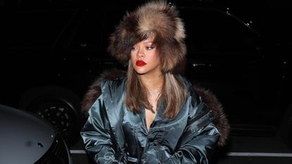 Rihanna in a brown fur hat, jacket, and jeans