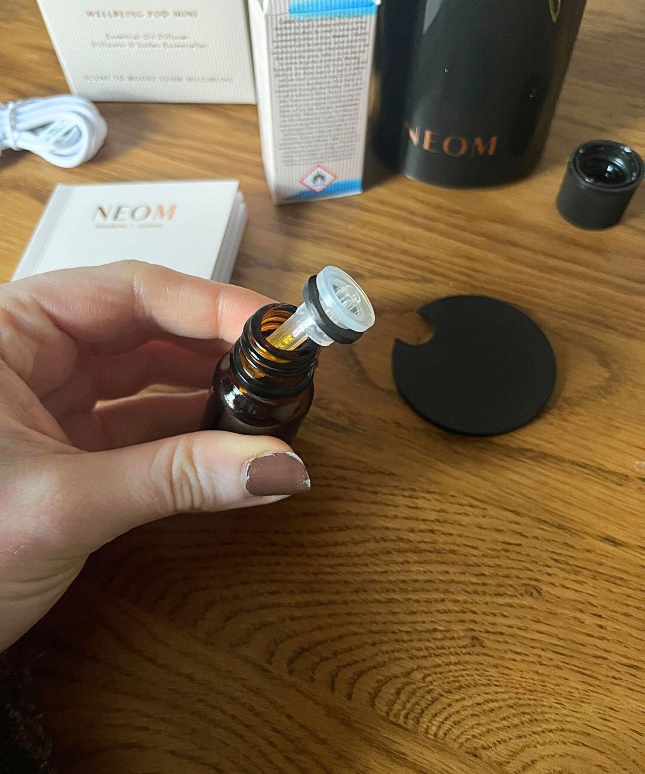 Removing the cap from the NEOM essential oil bottle
