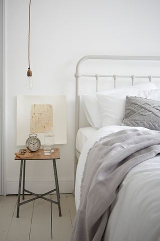 white bedroom with industrial bulb hanging down the side of the bed