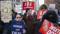 People holding banners chant during a rally outside Jacob K. Javits Federal Building against the firings of thousands of federal workers