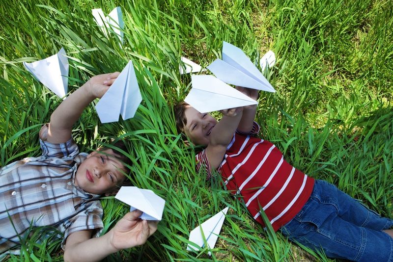 Two boys play with paper airplanes.