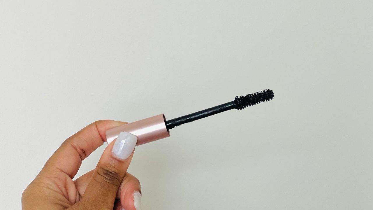 A person holding a rose gold L'Oreal mascara wand for the best L'Oreal mascara.
