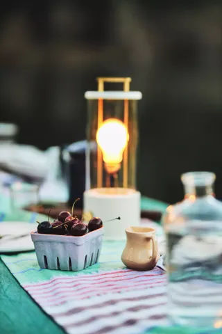 teal and purple outdoor table decor with a purple ceramic fruit basket holding cherries