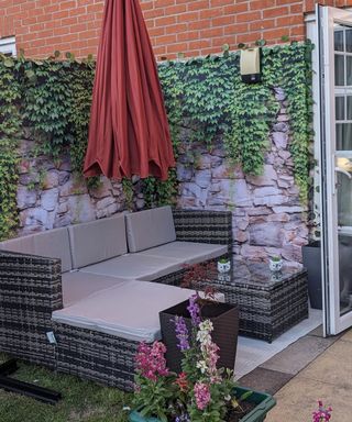A garden shower curtain with ivy and stone wall print attached to a fene in a garden seating area