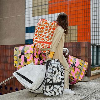 women with multiple coloured bag and stairs with multicoloured wall