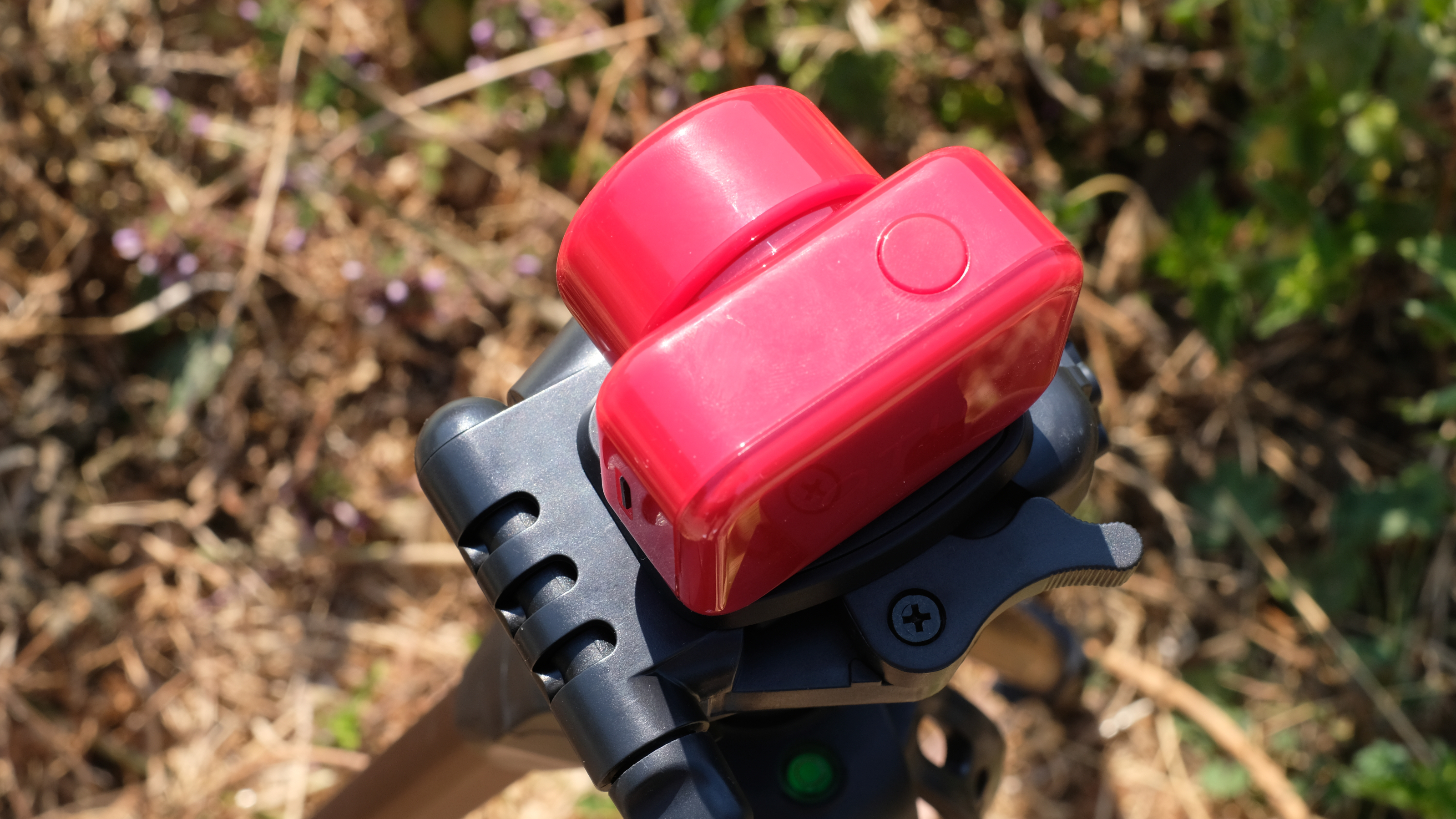 Photograph of the ATLi Eon time-lapse camera in red, top view showing power button
