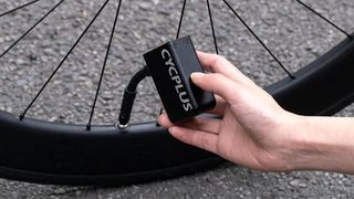 The Cycplus AS2 Electric Mini Pump being used to inflate road bike tyre