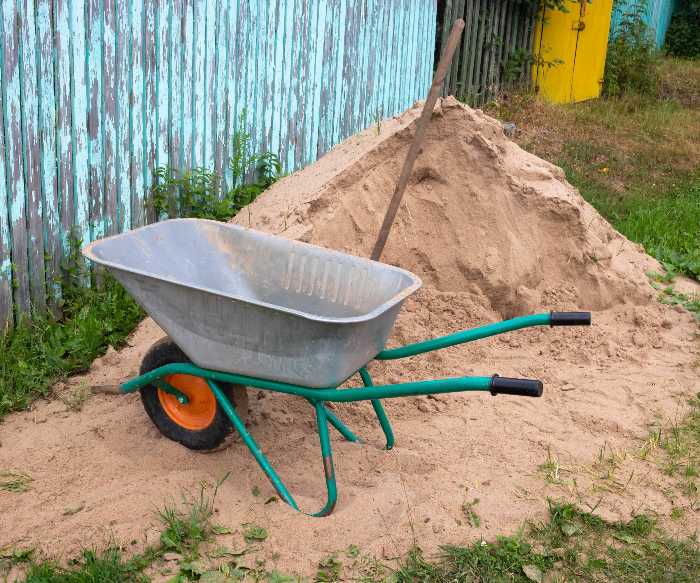 A wheelbarrow next to a pile of sand