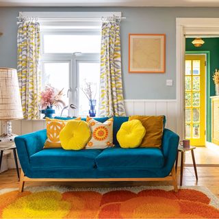 blue living room with blue velvet sofa and orange rug