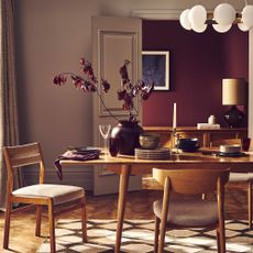Wooden dining table and chairs in front of a damson painted wall