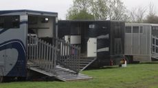 Horseboxes parked in a field with ramps down at a horse show.