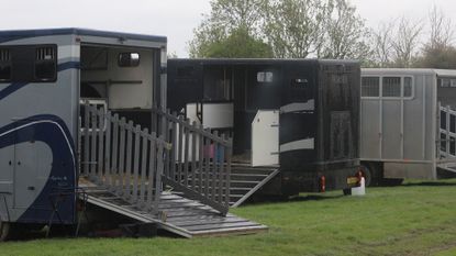 Horseboxes parked in a field with ramps down at a horse show.
