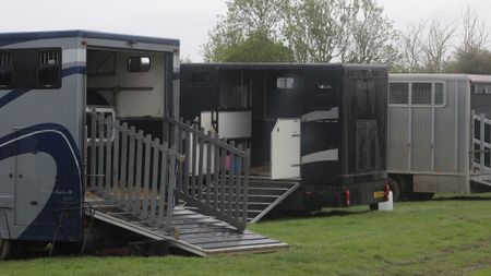 Horseboxes parked in a field with ramps down at a horse show.