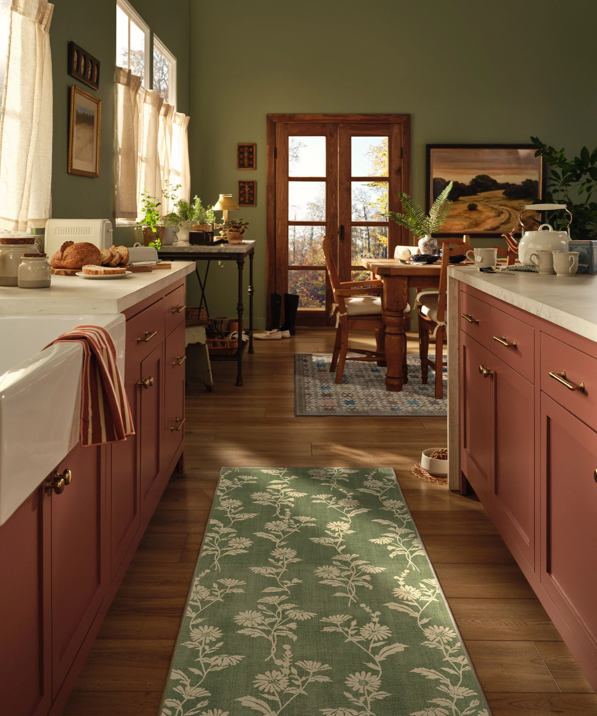 a kitchen with red cabinetry and a green floral runner rug on the floor