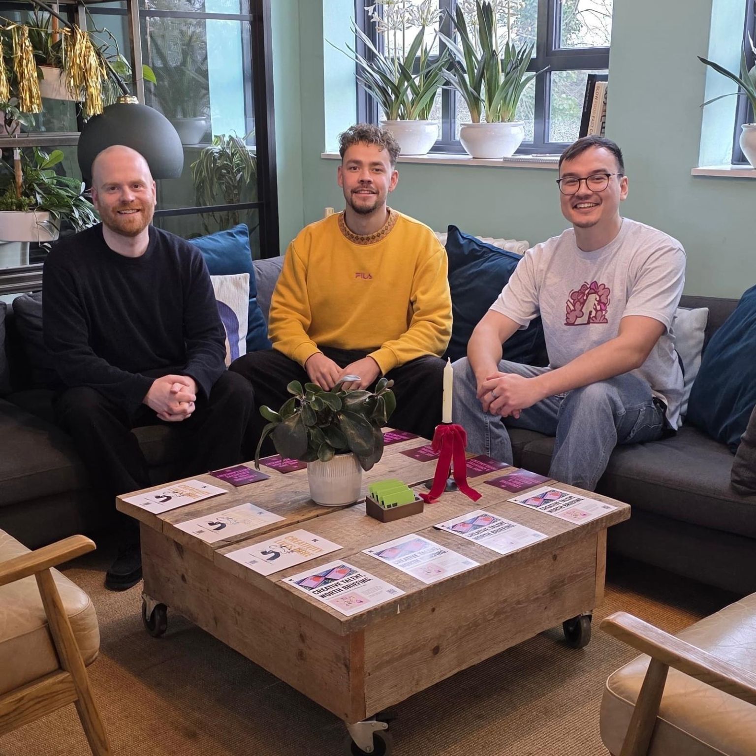 three men sitting on a sofa in front of a coffee table