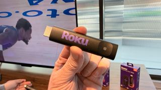 Roku Streaming Stick in hand.