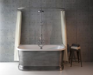 grey bathroom with grey studded wall, chrome roll top, shower ring and curtain, stool