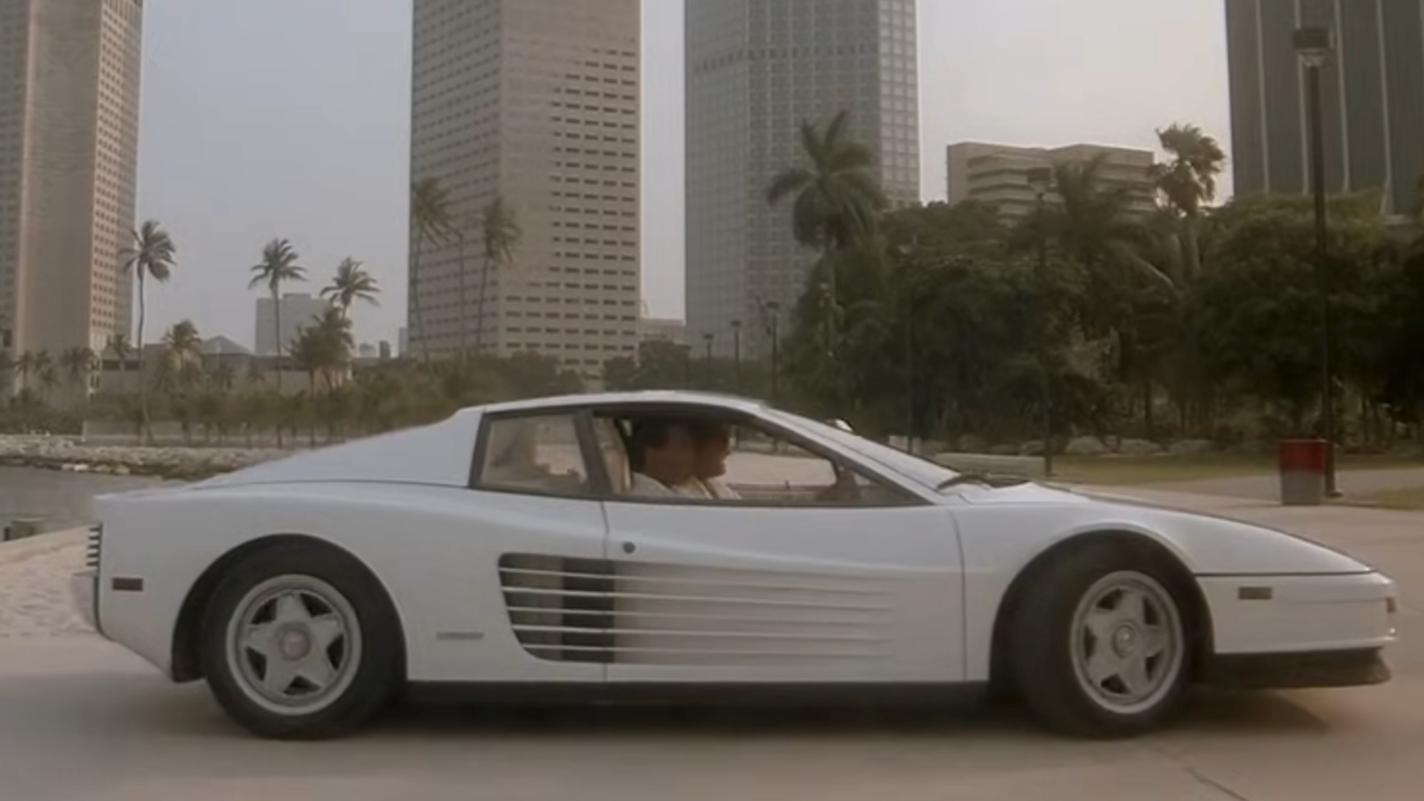 Crockett and Tubbs in a white Ferrari with the Miami Skyline behind them.