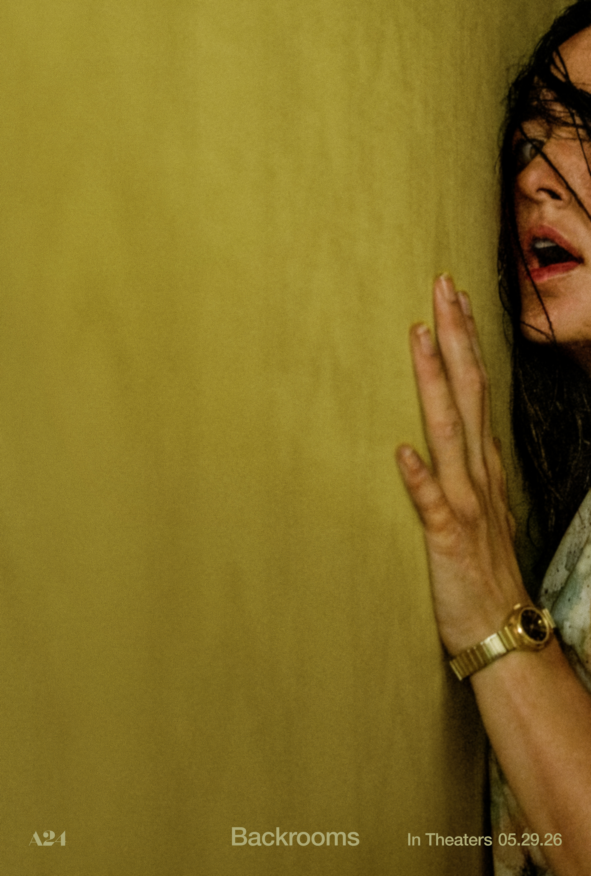 A pale yellow film set with textural wallpaper, minimal decor, and people wandering through it.