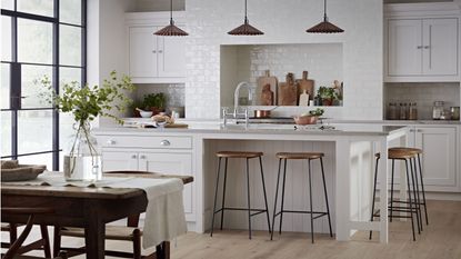 dark blue kitchen cabinets and island with 3 pendant lights and paintings on a wall