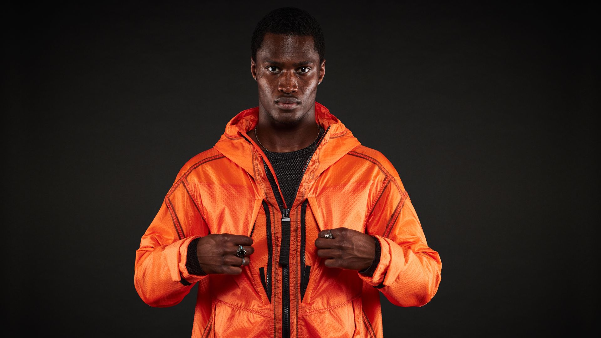 a male model wearing an orange coat with multiple pockets